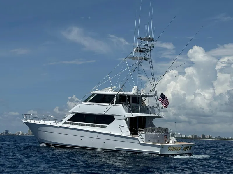 Slide: The Image of 1994 Hatteras 82 Convertible yacht cruising on open water under a clear sky. - 2