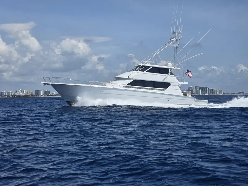 Slide: The Image of 1994 Hatteras 82 Convertible yacht cruising on open sea with city skyline in background. - 3