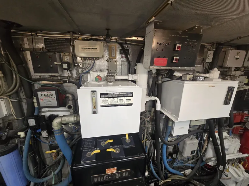 Slide: The Image of Engine room of a 1994 Hatteras 82 Convertible yacht, featuring complex machinery and control panels. - 49