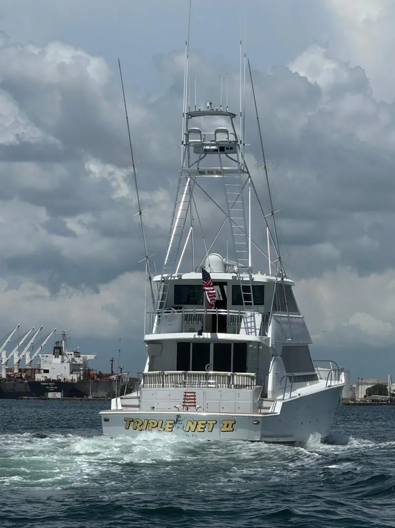 Slide: The Image of 1994 Hatteras 82 Convertible yacht cruising in open water under cloudy skies. - 5