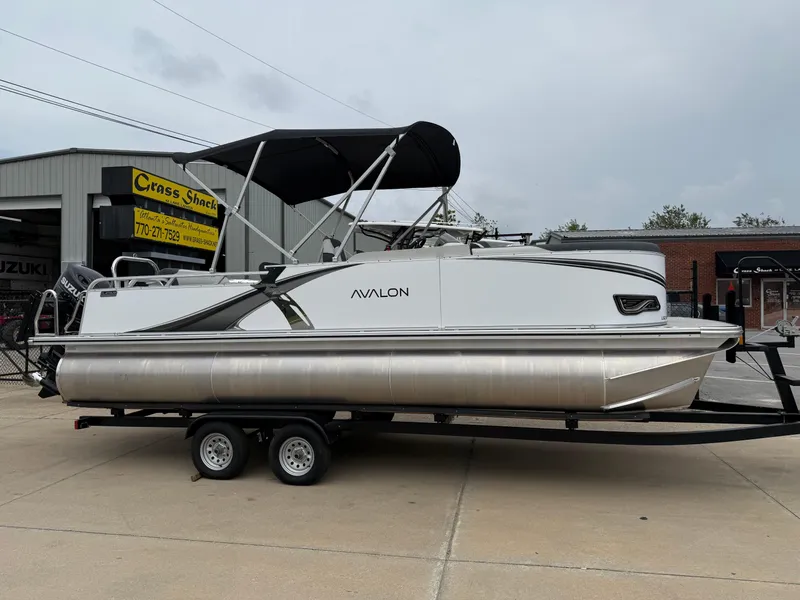 The Image of 2025 Avalon LSZ Versatile Rear Lounger pontoon boat on trailer, parked outside dealership. - 0