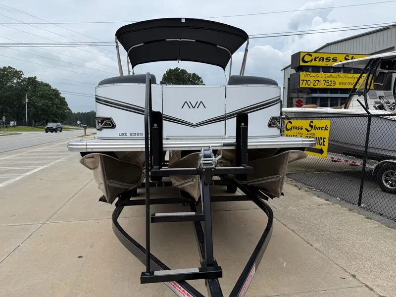 Slide: The Image of 2025 Avalon LSZ Versatile Rear Lounger boat on trailer, parked near a dealership. - 3