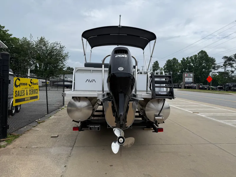 Slide: The Image of 2025 Avalon LSZ Versatile Rear Lounger pontoon boat with powerful outboard motor, parked outdoors. - 5