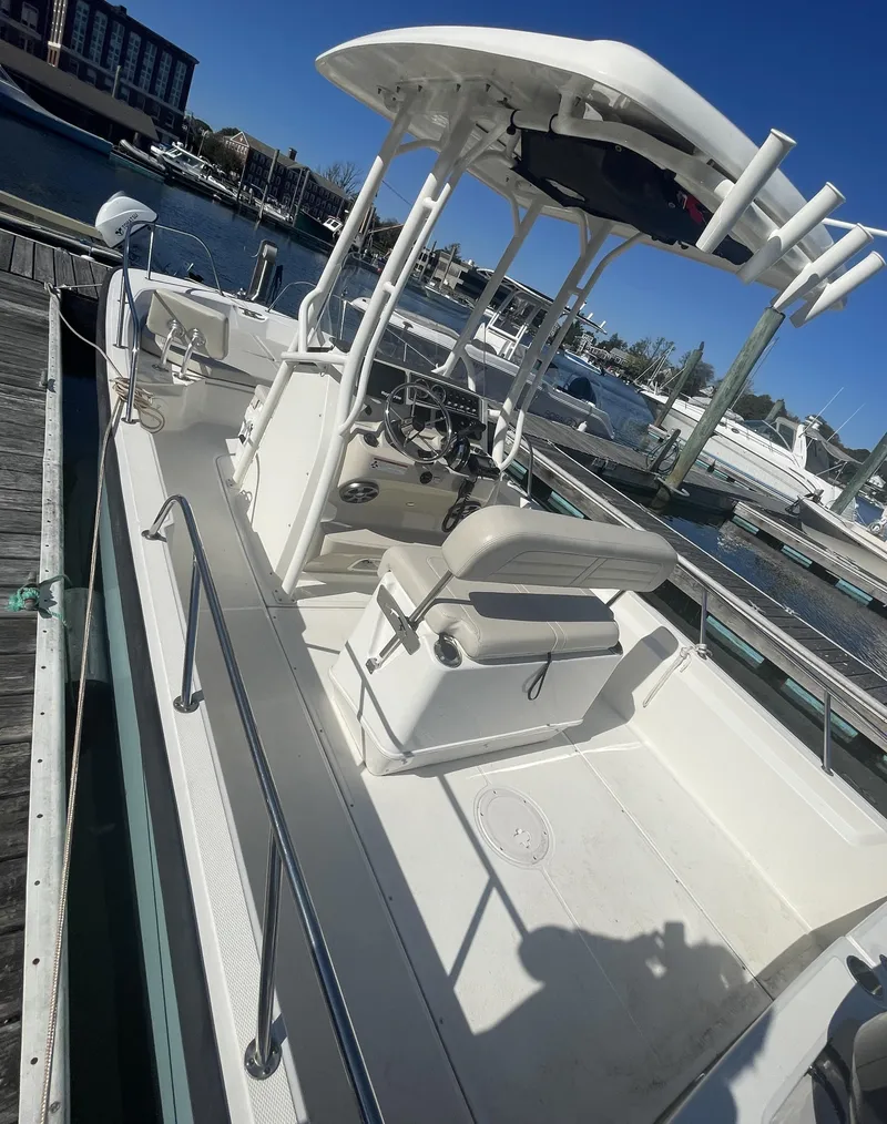 Slide: The Image of 2021 Boston Whaler 210 Montauk boat docked at marina, featuring center console and T-top. - 11