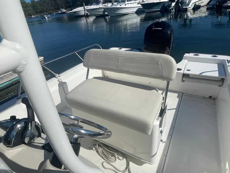 Slide: The Image of 2021 Boston Whaler 210 Montauk boat interior with seating and steering wheel, docked at marina. - 2