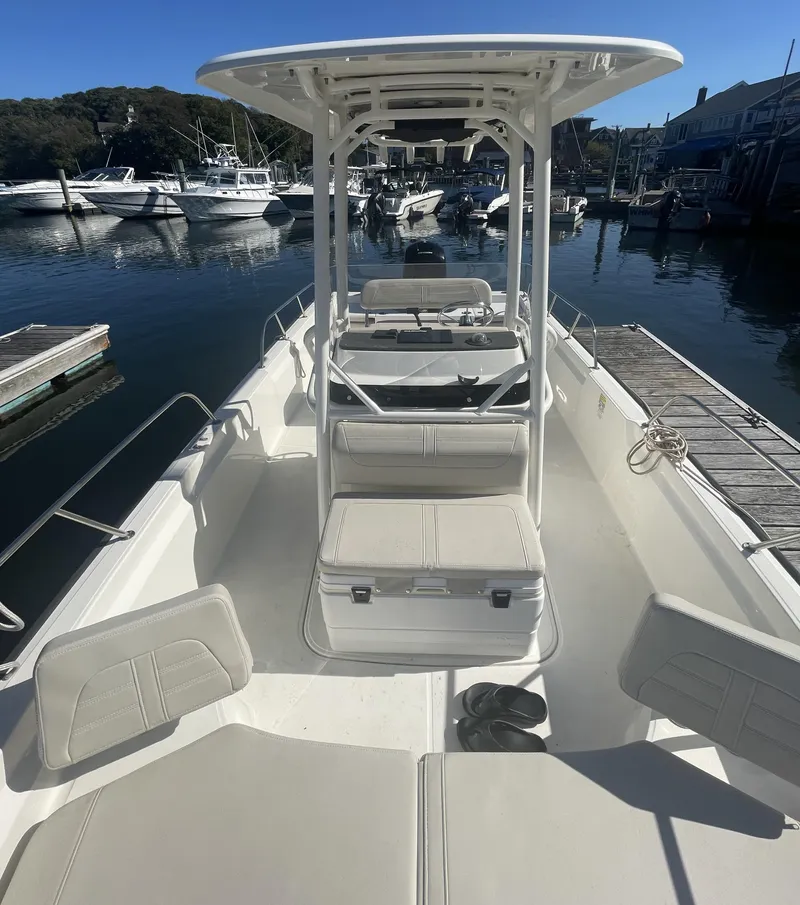 Slide: The Image of 2021 Boston Whaler 210 Montauk boat docked in a marina, featuring spacious seating and T-top. - 6