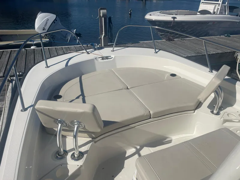 Slide: The Image of 2021 Boston Whaler 210 Montauk boat interior with cushioned seating, docked by the water. - 7