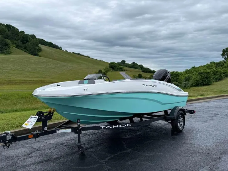 Slide: The Image of 2025 Tahoe T16 boat on trailer, parked on road with scenic green hills. - 2