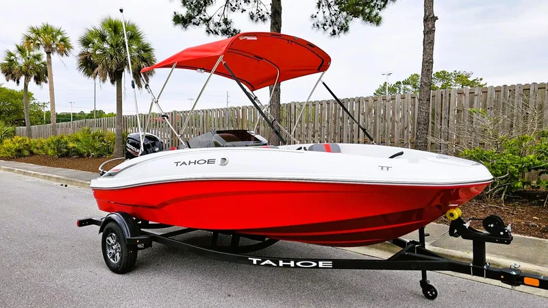 Slide: The Image of 2025 Tahoe T16 boat with red hull and canopy on a trailer, parked near palm trees. - 4