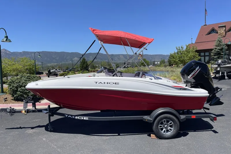 The Image of 2025 Tahoe T16 boat with red hull and canopy, parked on a trailer outdoors. - 0