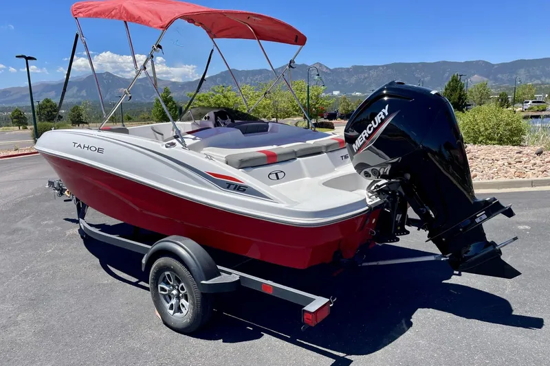 Slide: The Image of 2025 Tahoe T16 boat with red canopy and Mercury engine, parked outdoors. - 1