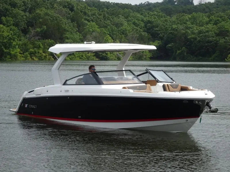 The Image of 2025 Cobalt R31 boat cruising on a serene lake with lush green forest backdrop. - 0