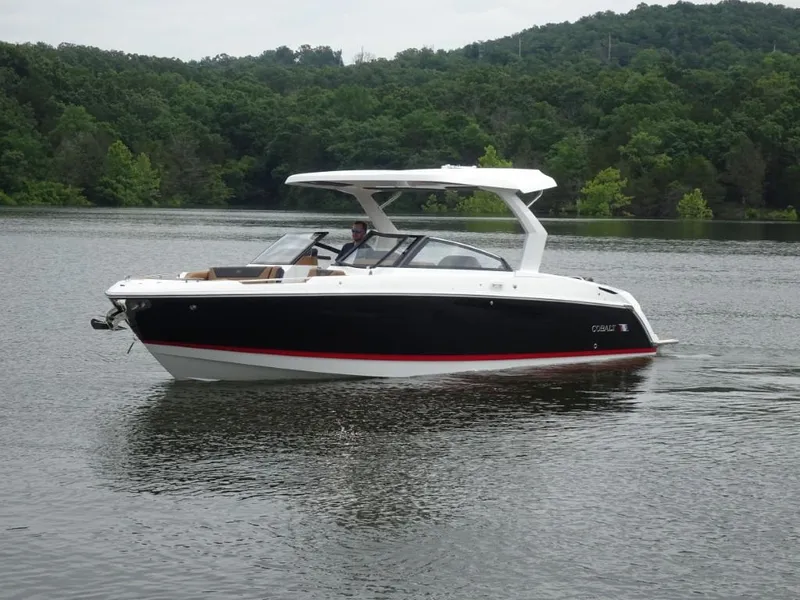 Slide: The Image of 2025 Cobalt R31 boat cruising on a serene lake with lush green forest backdrop. - 6