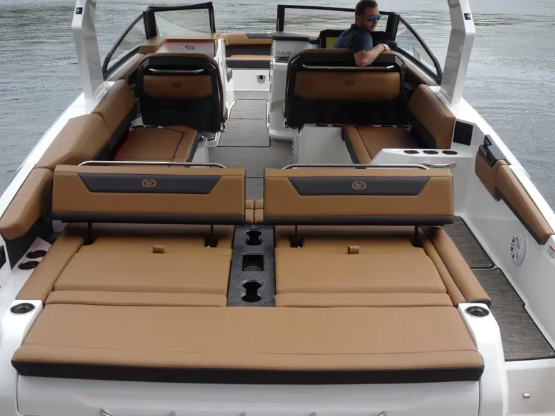 Slide: The Image of 2025 Cobalt R31 boat interior with tan seating and cup holders on a calm water backdrop. - 8