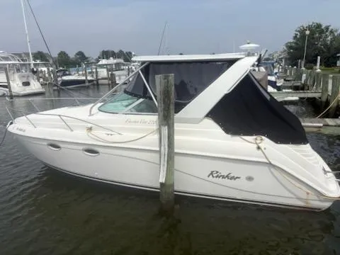 Slide: The Image of 1999 Rinker Fiesta Vee boat docked at a marina, featuring a white hull and black canopy. - 2