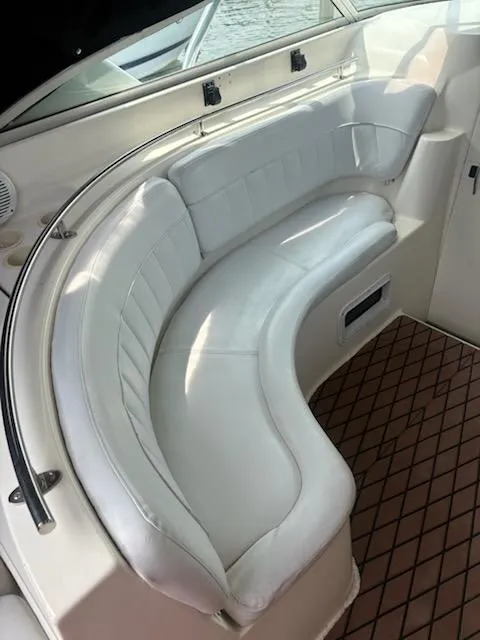 Slide: The Image of 1999 Rinker Fiesta Vee boat interior with white curved seating and brown flooring. - 6