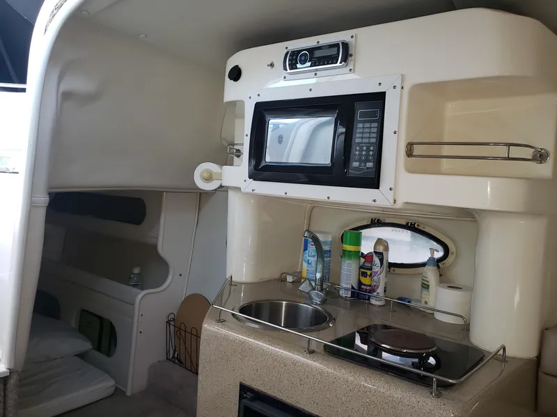 Slide: The Image of 1999 Rinker Fiesta Vee boat interior with kitchenette, microwave, sink, and storage space. - 8