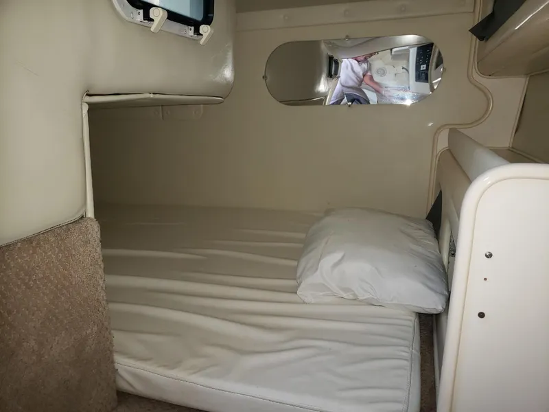 Slide: The Image of 1999 Rinker Fiesta Vee cabin interior with bed and pillow, showcasing compact sleeping area. - 9