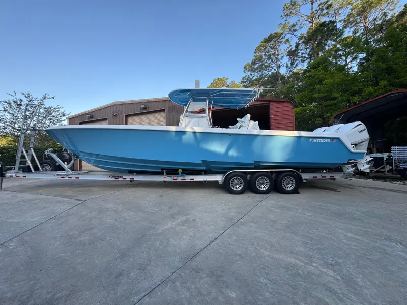 Slide: The Image of 2025 Contender 39ST boat on trailer, blue hull, parked outdoors. - 1