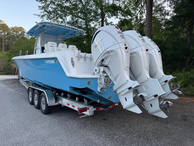 Slide: The Image of 2025 Contender 39ST boat on trailer with triple outboard engines, parked outdoors. - 10