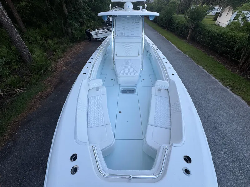 Slide: The Image of 2025 Contender 39ST boat with spacious deck and seating, parked on a tree-lined road. - 12