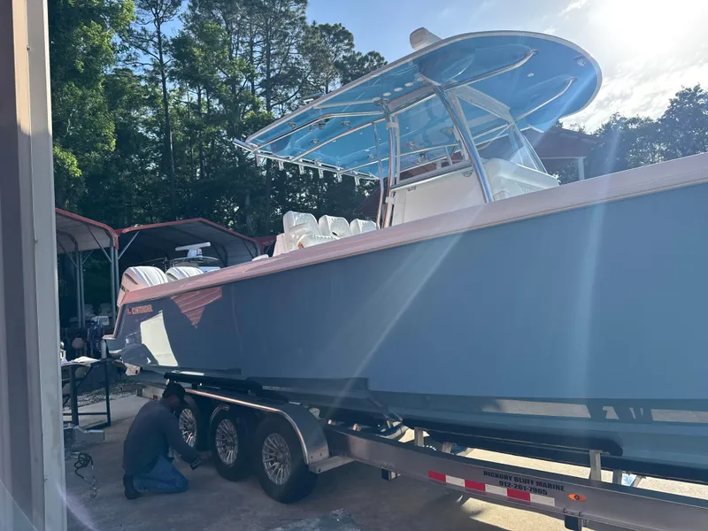 Slide: The Image of 2025 Contender 39ST boat on trailer, parked outdoors with trees in the background. - 2