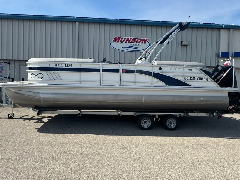 Slide: The Image of 2023 Bennington 24 LXFB pontoon boat on trailer, under cloudy sky. - 1