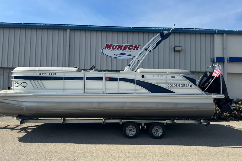 Slide: The Image of 2023 Bennington 24 LXFB pontoon boat on trailer under cloudy sky. - 2