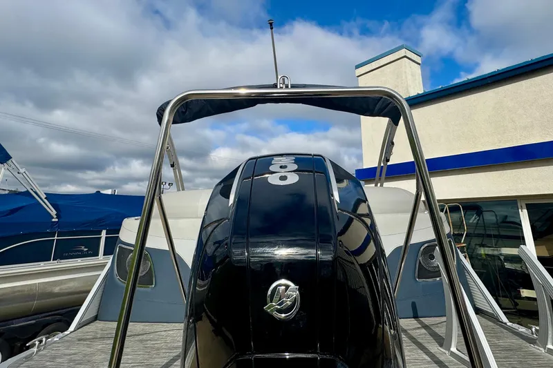 Slide: The Image of 2023 Bennington 24 LXFB boat with powerful outboard motor, docked under cloudy sky. - 33