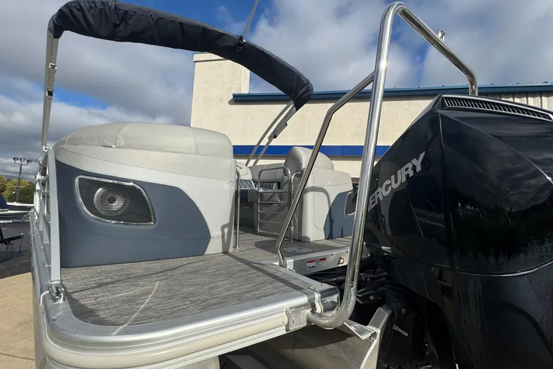 Slide: The Image of 2023 Bennington 24 LXFB pontoon boat with Mercury engine, showcasing rear seating and deck. - 34
