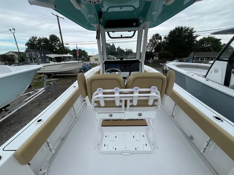 Slide: The Image of 2025 Sportsman Open 232 Center Console boat interior with beige seating and rod holders. - 7