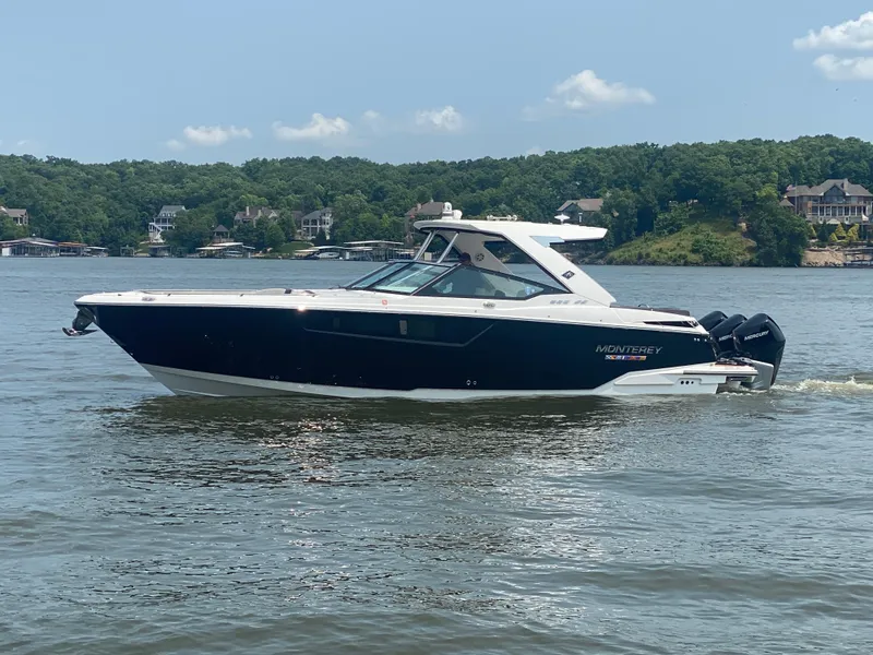 Slide: The Image of 2022 Monterey 385 Super Sport boat cruising on a lake with scenic background. - 0