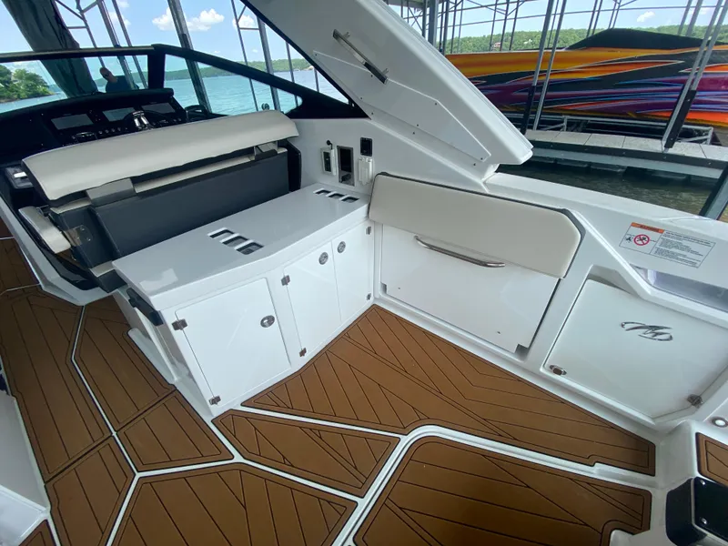 Slide: The Image of 2022 Monterey 385 Super Sport boat interior with sleek white cabinetry and wood-patterned flooring. - 22