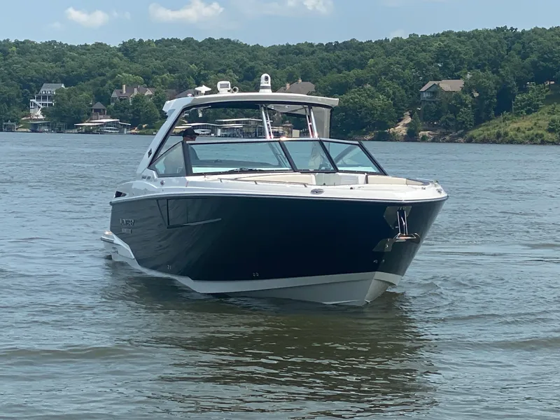 Slide: The Image of 2022 Monterey 385 Super Sport boat cruising on a serene lake with lush green shoreline. - 3