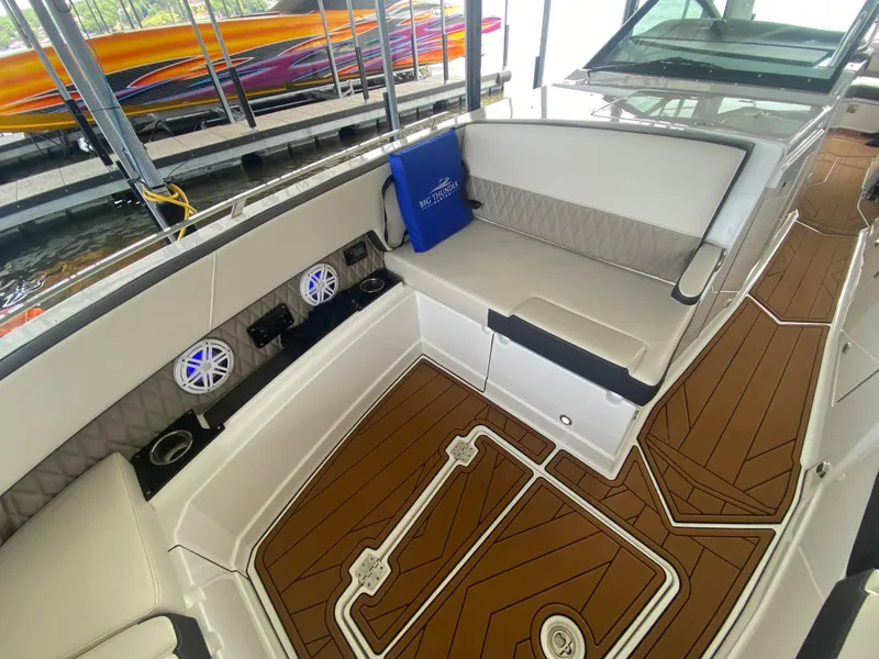 Slide: The Image of 2022 Monterey 385 Super Sport boat interior with cushioned seating and wood-patterned flooring. - 45