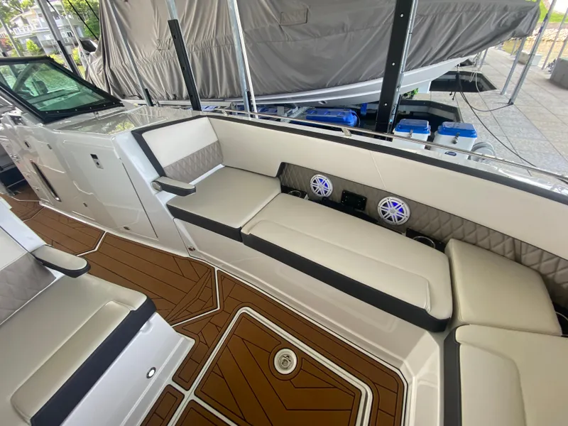 Slide: The Image of 2022 Monterey 385 Super Sport boat interior with cushioned seating and wood-patterned flooring. - 46