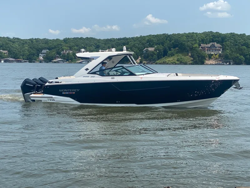 Slide: The Image of 2022 Monterey 385 Super Sport boat cruising on a lake with scenic background. - 5