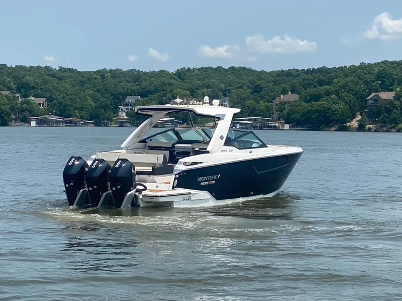 Slide: The Image of 2022 Monterey 385 Super Sport boat cruising on a lake with scenic forested shoreline. - 6