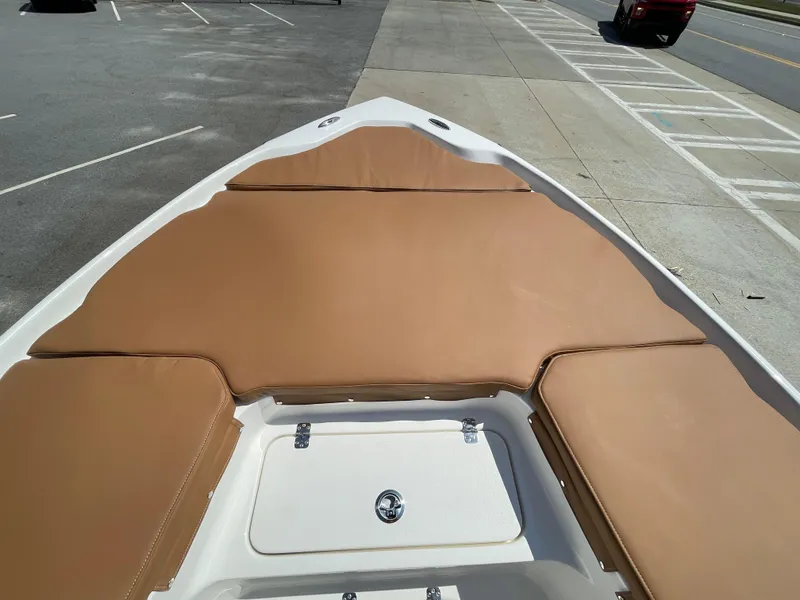 Slide: The Image of 2025 Key West 250BR boat with tan cushioned seating, docked near a road. - 13