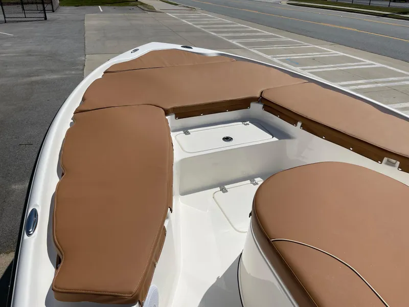 Slide: The Image of 2025 Key West 250BR boat with tan cushioned seating, docked in a parking area. - 14