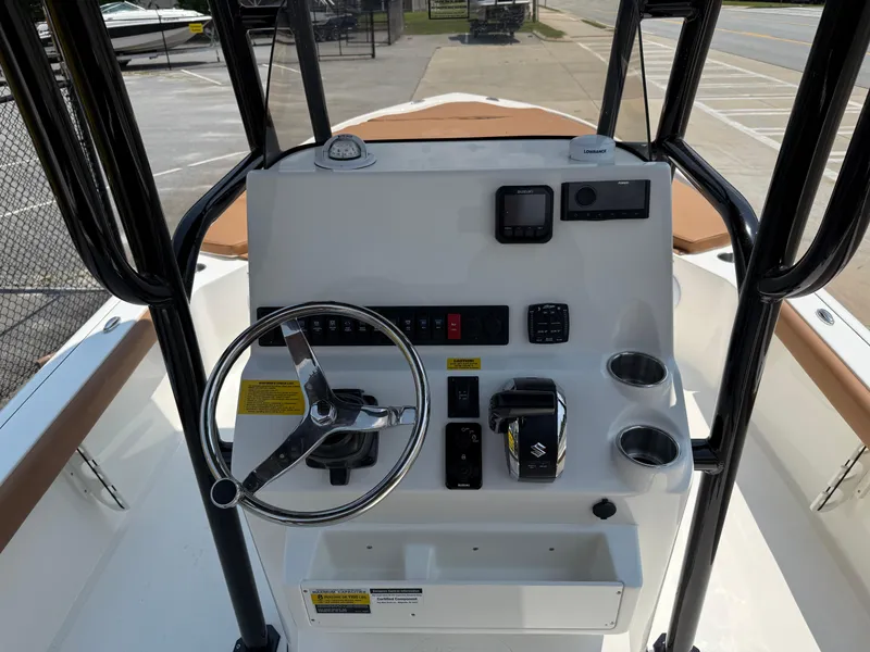 Slide: The Image of 2025 Key West 250BR boat with brown cushioned seating, parked near a road. - 20