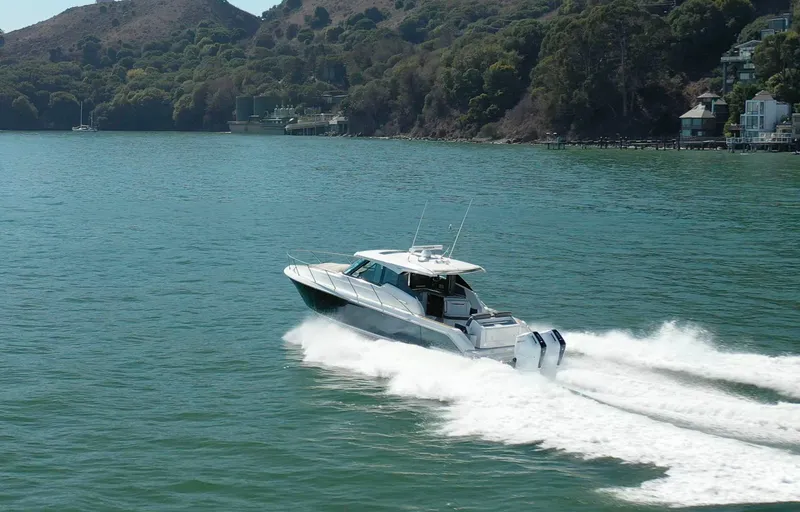 Slide: The Image of 2022 Tiara Yachts 43 LE cruising on a scenic lake with lush hills in the background. - 2