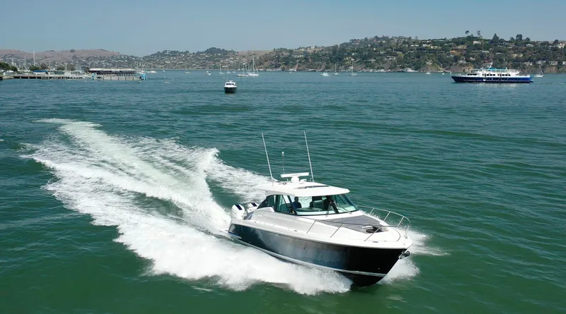 Slide: The Image of 2022 Tiara Yachts 43 LE cruising on a scenic bay with hills in the background. - 5