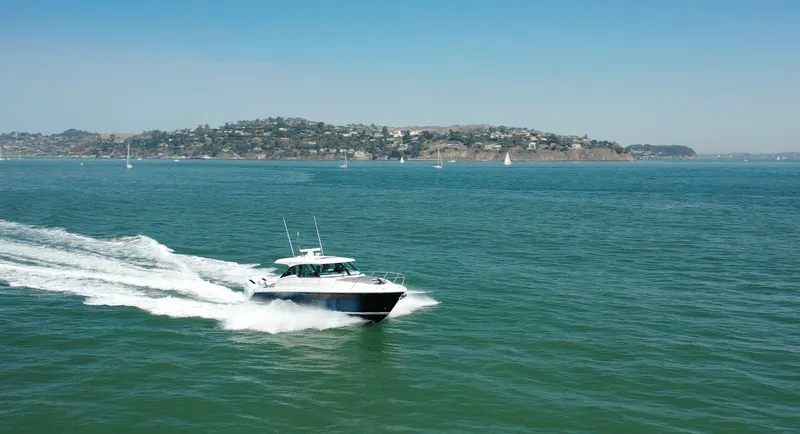 Slide: The Image of 2022 Tiara Yachts 43 LE cruising on open water with scenic coastline backdrop. - 6