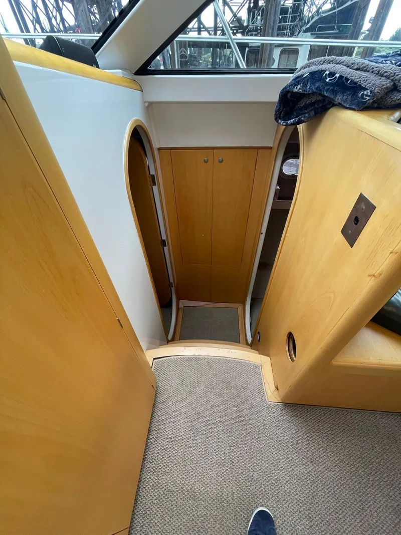 Slide: The Image of Interior of 1997 Roger Hill 11.2m Powercat, featuring wooden cabinetry and carpeted flooring. - 11
