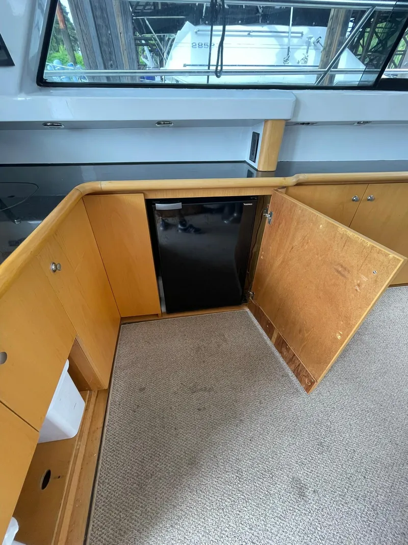 Slide: The Image of Interior of 1997 Roger Hill 11.2m Powercat with open wooden cabinet and mini fridge. - 18