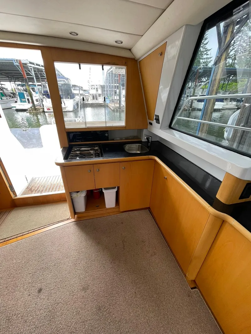 Slide: The Image of Interior of 1997 Roger Hill 11.2m Powercat, featuring a compact kitchen with a waterfront view. - 19