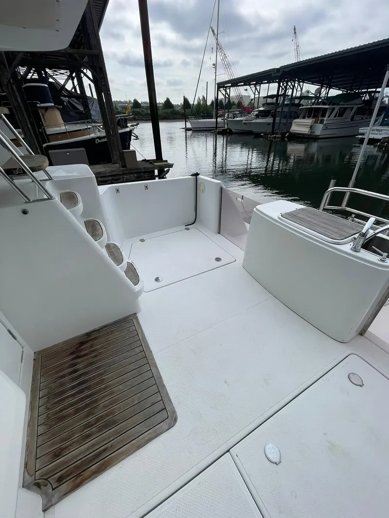 Slide: The Image of 1997 Roger Hill 11.2m Powercat deck with marina view, featuring clean white surfaces. - 2