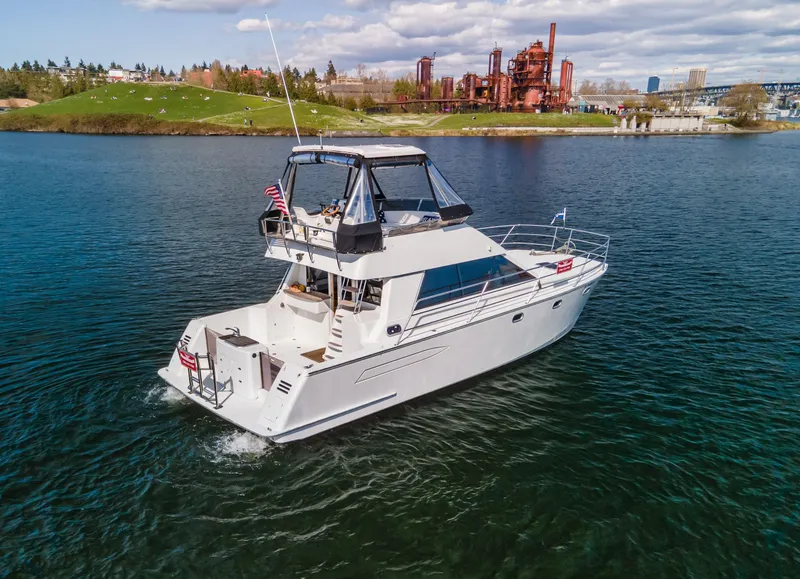 Slide: The Image of 1997 Roger Hill 11.2m Powercat cruising on a scenic lake with industrial backdrop. - 38