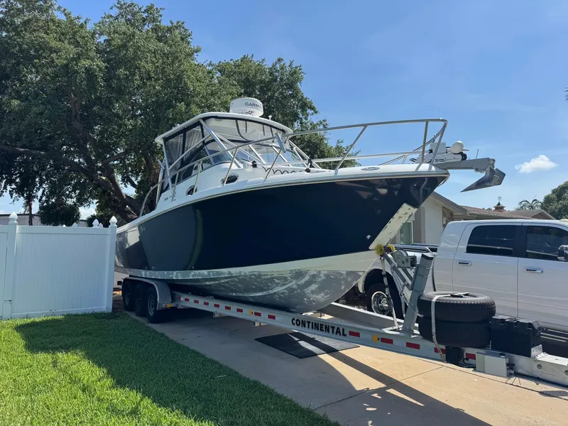 Slide: The Image of 2008 Sailfish 30-06 Express boat on trailer, parked in driveway under clear blue sky. - 5
